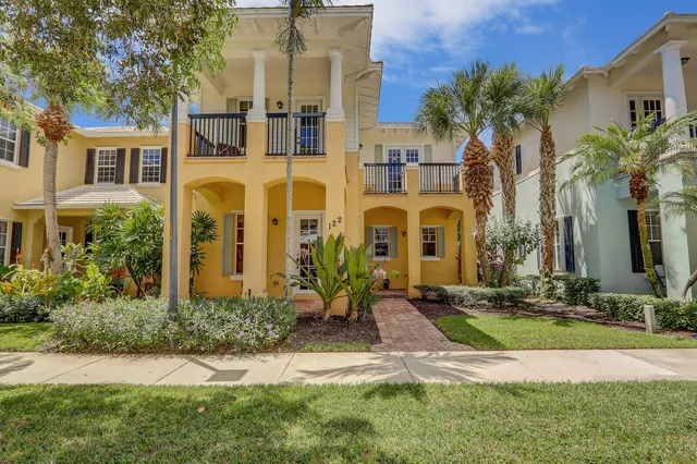 a front view of a multi story residential apartment building with yard and green space