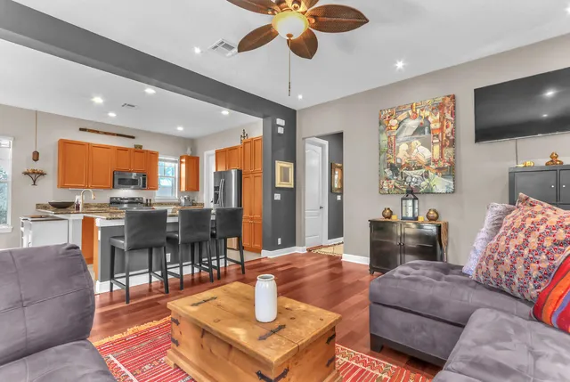 a kitchen with stainless steel appliances granite countertop a stove top oven a sink dishwasher a dining table and chairs with wooden floor