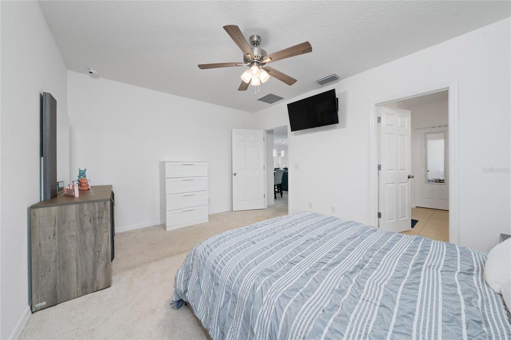 669 Jupiter Beach Road Groveland, FL 34736 - Photo 11 of 41 a bedroom with a large bed and a flat screen tv