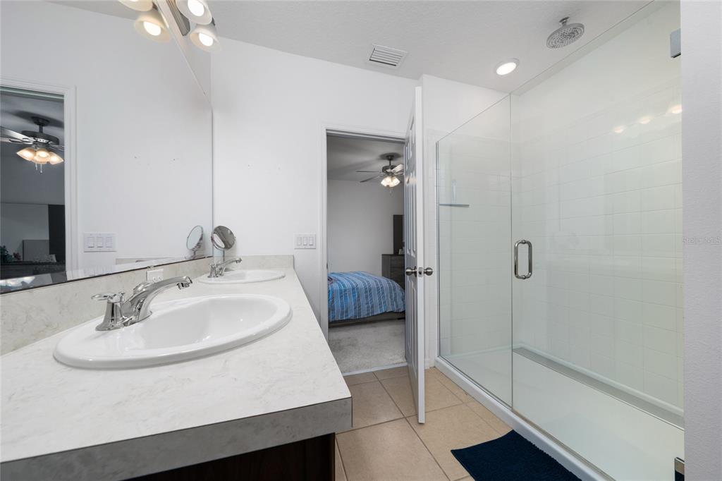 669 Jupiter Beach Road Groveland, FL 34736 - Photo 13 of 41 a en suite bathroom with a sink a mirror and a shower