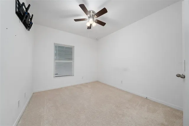 an empty room with ceiling fan and window