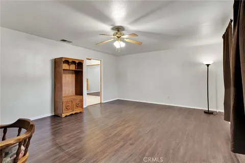 a view of an empty room with wooden floor and a ceiling fan
