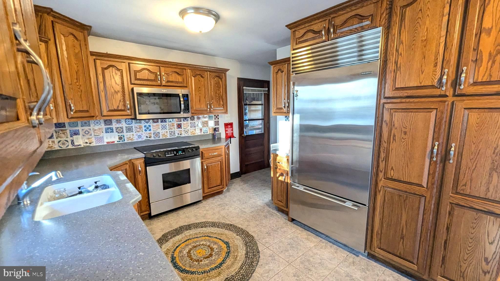 429 Simpson Street Bellefonte, PA 16823 - Photo 15 of 27 a kitchen with stainless steel appliances granite countertop a refrigerator a stove and a sink with wooden floor