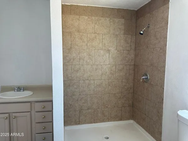a bathroom with a granite countertop sink a toilet and shower