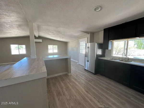 a kitchen with stainless steel appliances granite countertop a refrigerator a sink dishwasher a stove and black countertops with wooden floor