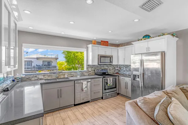 a kitchen with stainless steel appliances granite countertop a sink a stove a refrigerator and cabinets