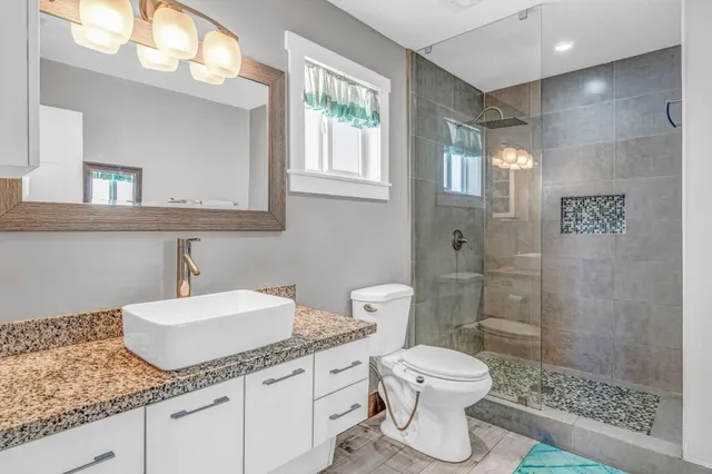 a bathroom with a granite countertop sink a toilet and a mirror