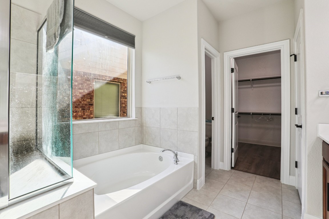 3602 Chaff Lane Pflugerville, TX 78660 - Photo 12 of 28 Bathroom with toilet, tile walls, tile patterned flooring, vanity, and a tub
