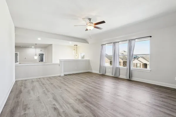 a view of an empty room with a window and wooden floor