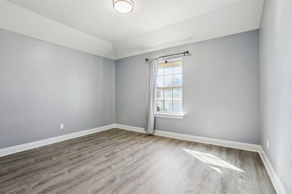 3602 Chaff Lane Pflugerville, TX 78660 - Photo 22 of 28 Empty room featuring hardwood / wood-style floors and lofted ceiling