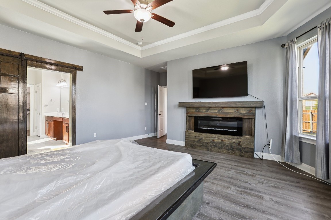 3602 Chaff Lane Pflugerville, TX 78660 - Photo 8 of 28 Bedroom featuring ceiling fan, connected bathroom, a tray ceiling, and a barn door
