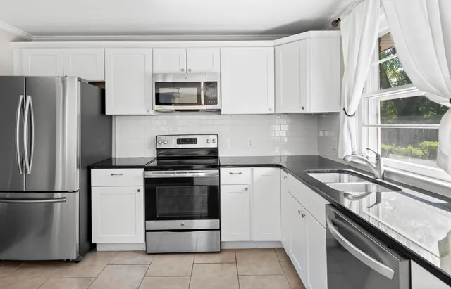 a kitchen with white cabinets stainless steel appliances and a window