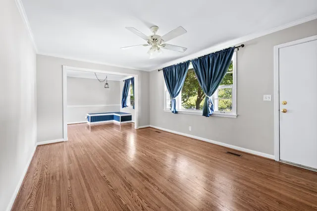 a view of an empty room with wooden floor and a window