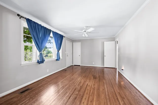 a view of an empty room with wooden floor and a window