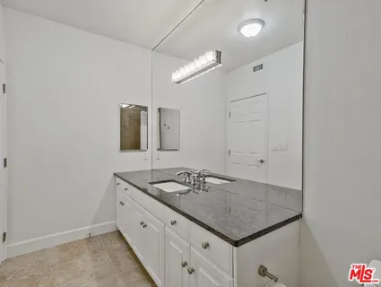 a bathroom with a granite countertop sink and a mirror