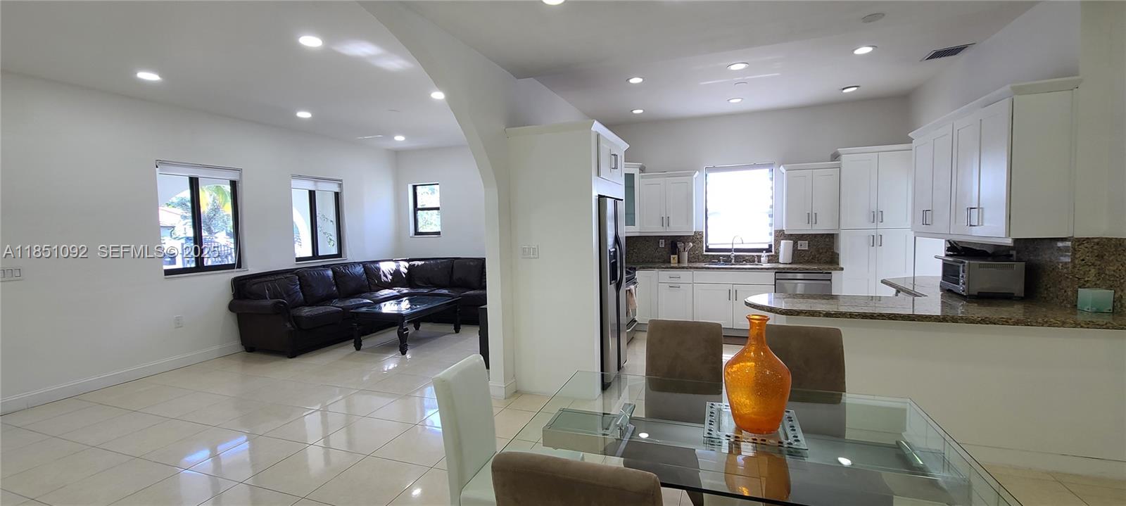 1721 Southwest 24th Terrace Miami, FL 33145 - Photo 19 of 80 a kitchen with stainless steel appliances granite countertop a refrigerator a sink a stove a dining table and chairs with wooden floor