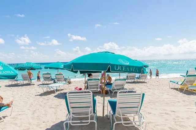 a view of a swimming pool with lawn chairs under an umbrella