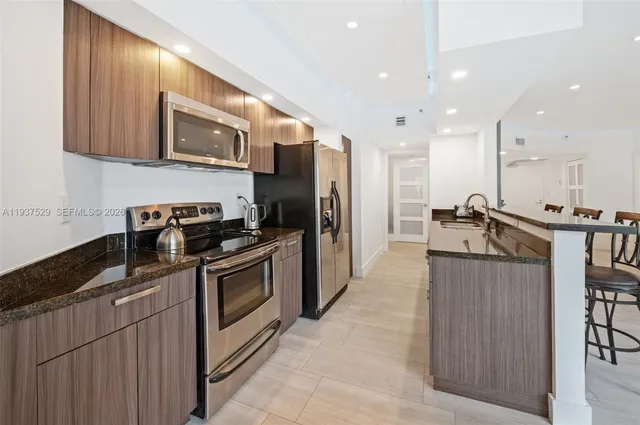 a kitchen with stainless steel appliances granite countertop a refrigerator a stove top oven a sink and dishwasher