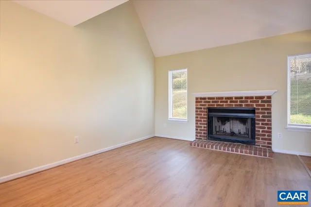 an empty room with wooden floor fireplace and window