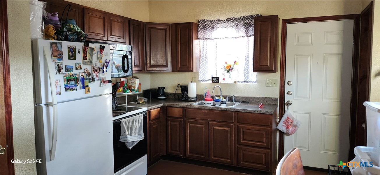 414 Harl Street Pleasanton, TX 78064 - Photo 9 of 28 a kitchen with a refrigerator and a sink