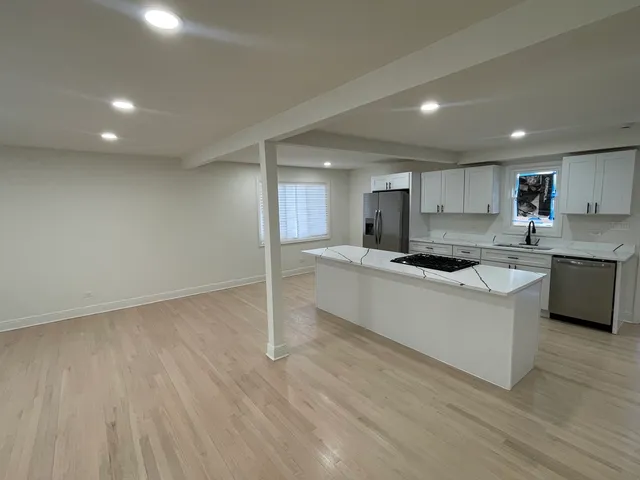 a large kitchen with a lot of counter space and wooden floor