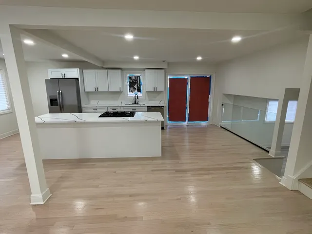 a large kitchen with kitchen island a sink a stove a refrigerator and white cabinets