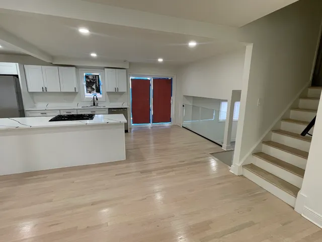 a large white kitchen with wooden floors and stainless steel appliances