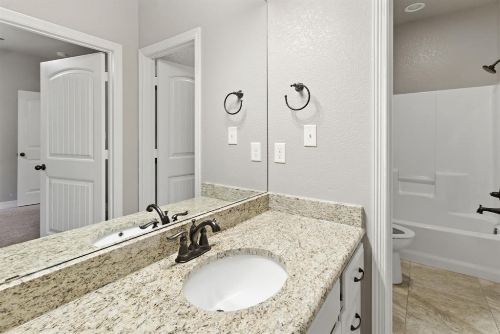 7765 Hickory Spring Lane Tyler, TX 75703 - Photo 32 of 38 Bathroom vanity featuring an integrated sink, bronze-finish faucet, and speckled countertop