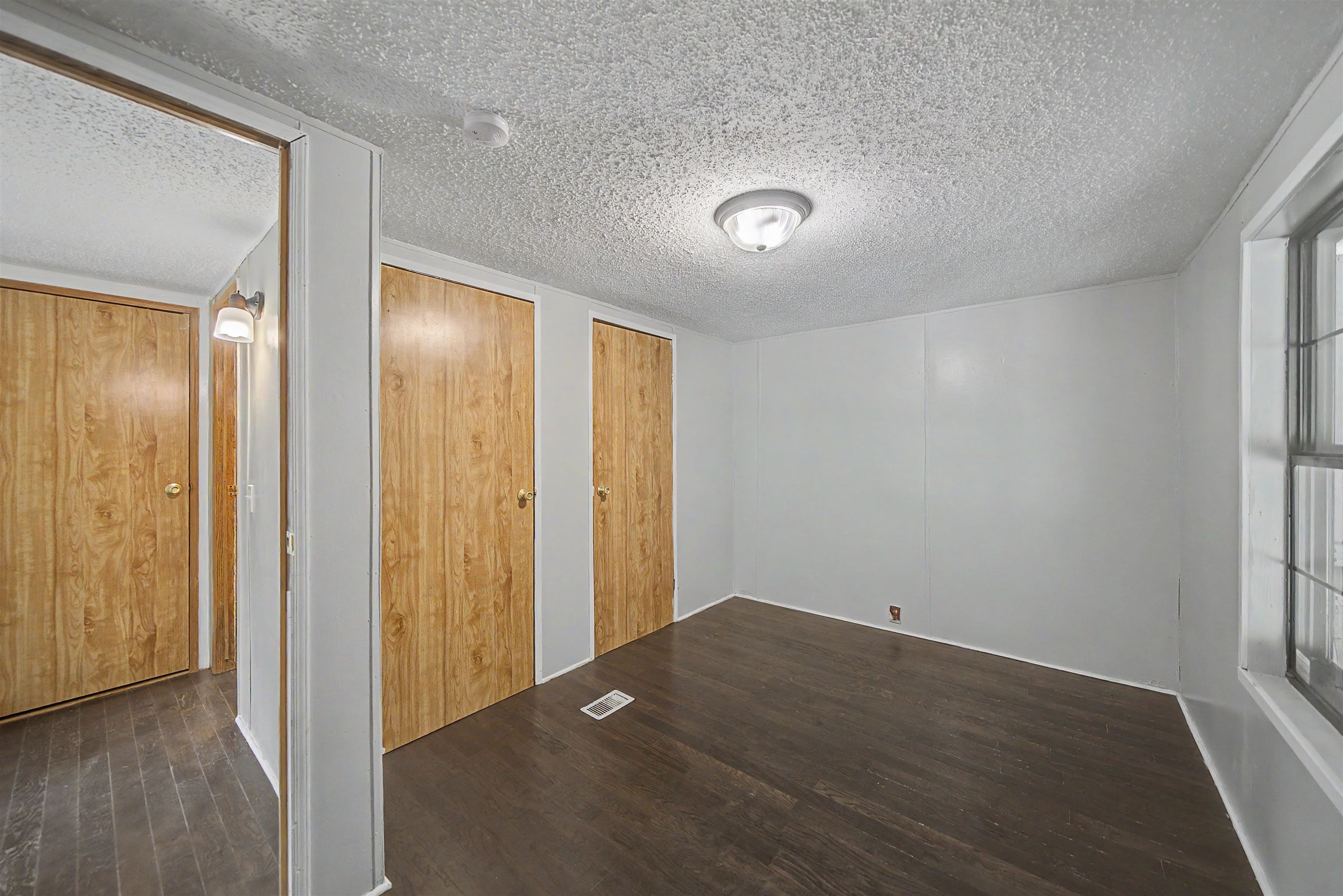 6264 45th Highway South Ramer, TN 38367 - Photo 23 of 24 Room featuring wood-finish flooring, light gray walls, a window with grid patterns, and two wood-look bi-fold doors