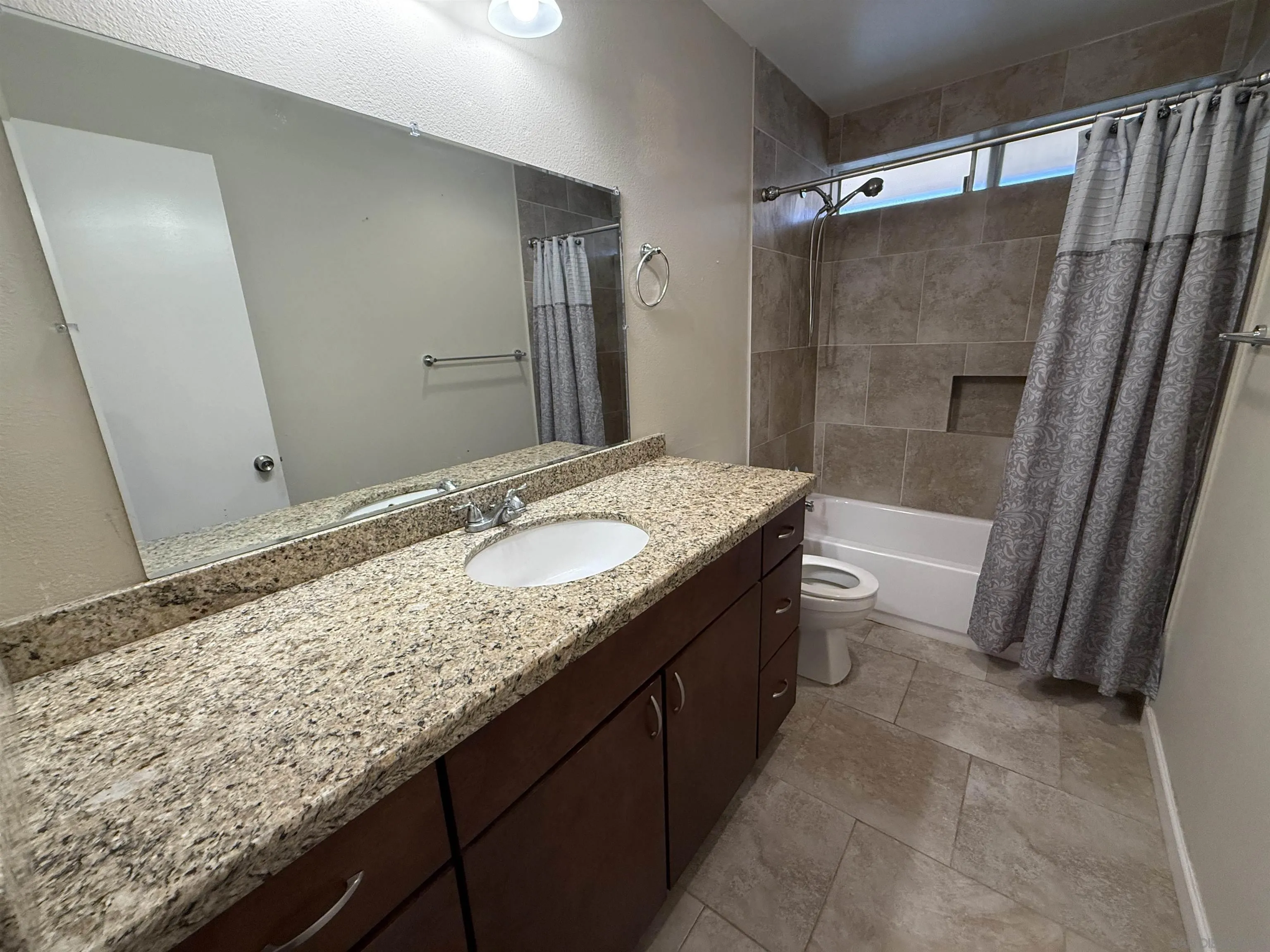 12608 Mantilla Road San Diego, CA 92128 - Photo 27 of 37 a bathroom with a granite countertop sink a mirror and shower