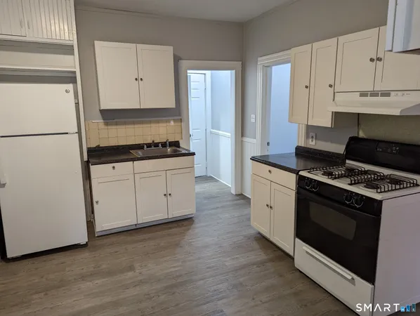 a kitchen with granite countertop white cabinets and white appliances