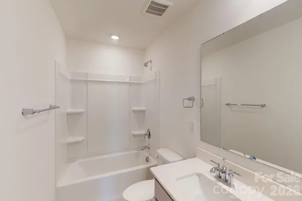 a bathroom with a bathtub shower sink vanity and toilet