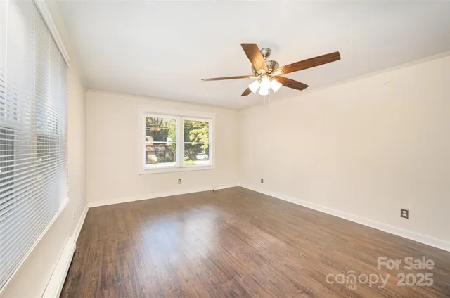 an empty room with wooden floor fan and windows