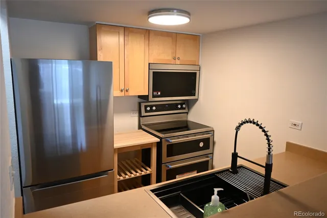 a kitchen with stainless steel appliances granite countertop a refrigerator and a stove top oven