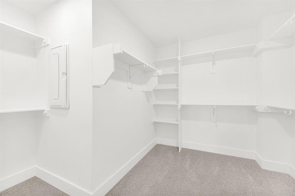 9471 Timberleaf Drive Dallas, TX 75243 - Photo 22 of 39 Walk-in closet featuring white built-in shelving, white walls, white trim, and light gray carpet flooring