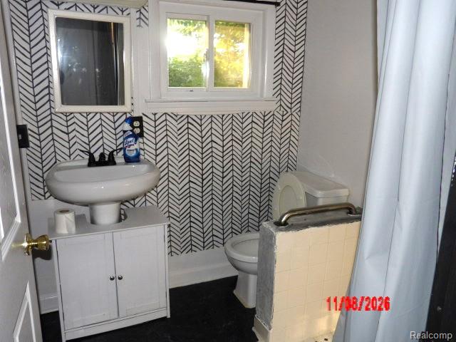 9384 Birch Run Road Millington, MI 48746 - Photo 8 of 12 Stylish bathroom featuring geometric chevron tile walls, pedestal sink with chrome fixtures, white vanity cabinetry, and black flooring