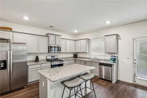 a kitchen with stainless steel appliances granite countertop a stove a sink a refrigerator white cabinets and a refrigerator