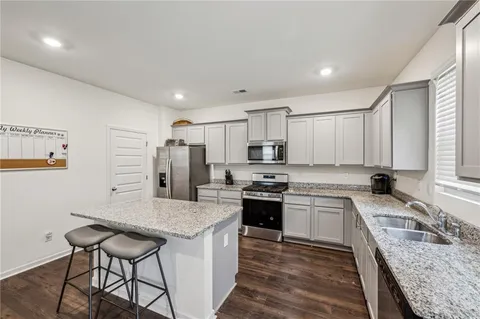 a kitchen with stainless steel appliances granite countertop a sink stove refrigerator and cabinets