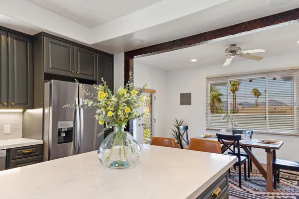 a dining room with furniture a potted plant and open kitchen view