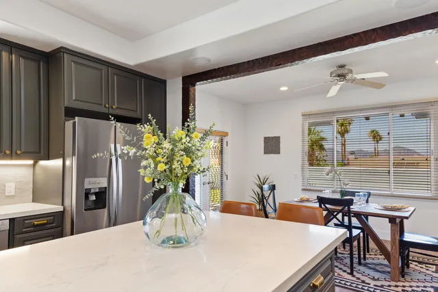 a dining room with furniture a potted plant and open kitchen view