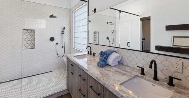 a bathroom with a granite countertop sink a mirror and shower