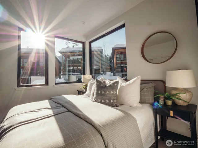 a bedroom with bed and a large mirror with a large window