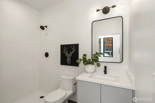 a bathroom with a toilet sink vanity granite and mirror