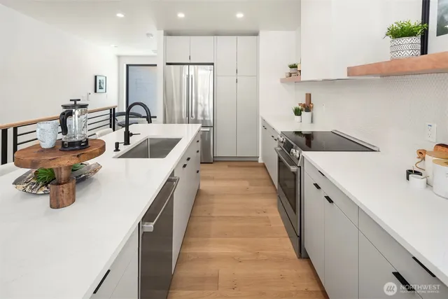 a large white kitchen with a sink a refrigerator and wooden floor
