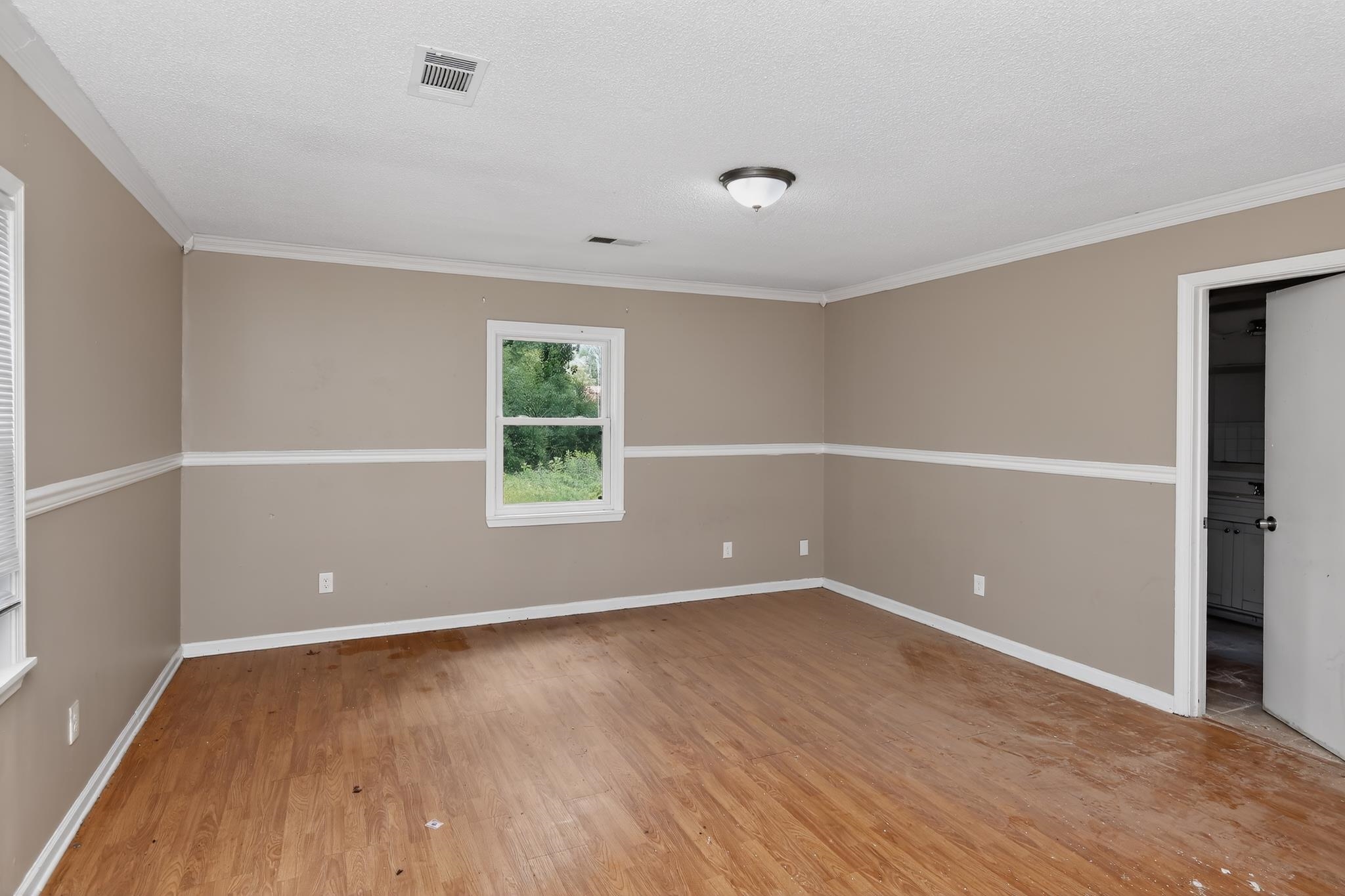 1403 Old Hickory Road Memphis, TN 38116 - Photo 11 of 31 Spacious room featuring wood-finish flooring, neutral two-tone walls with white trim, a double-paned window, and a ceiling-mounted light fixture