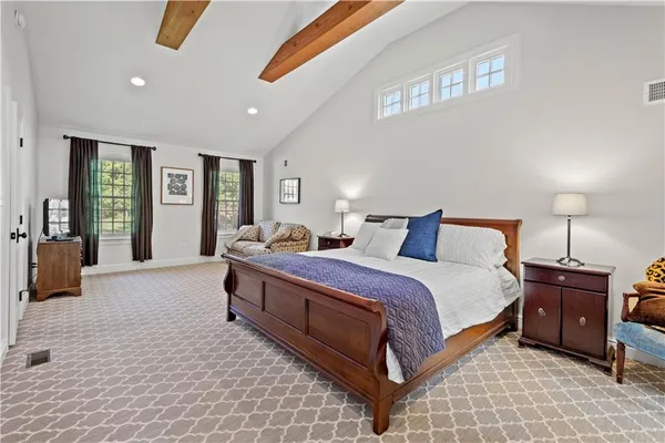 a bedroom with a bed couches and paintings on the wall