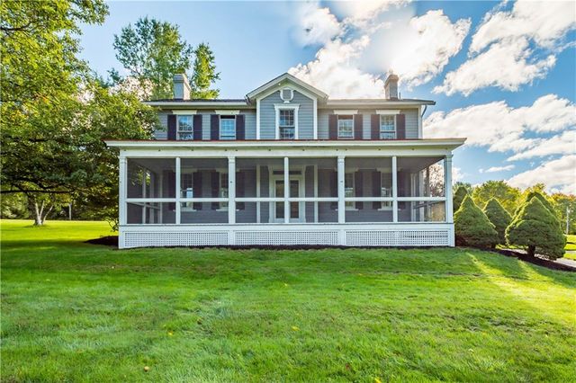 a view of a brick house with a big yard and large trees