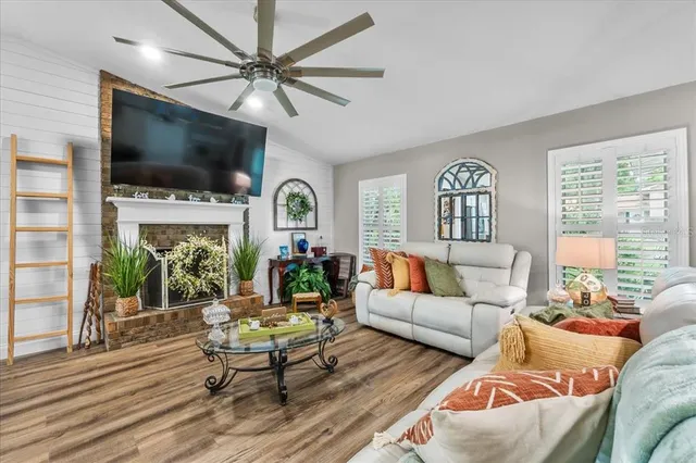 a living room with furniture kitchen view and a wooden floor