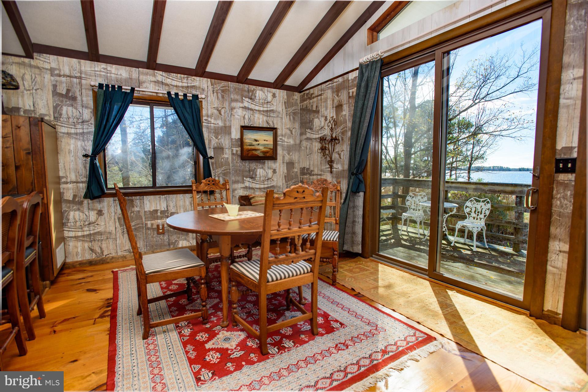 1308 Town Point Road Cambridge, MD 21613 - Photo 38 of 61 a dining room with furniture a rug and a floor to ceiling window