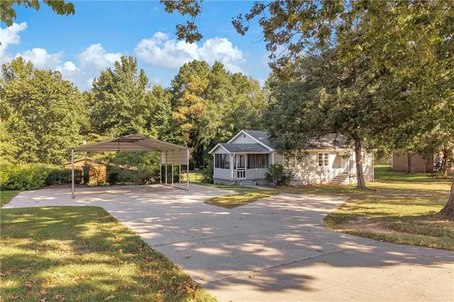a view of a house with a yard and large trees